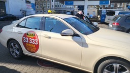 Ein gelbes Taxi, dass vor einer Tankstelle steht. 