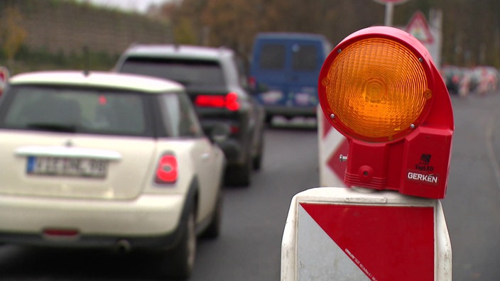 Im Vordergrund sieht man eine Leitbake und im Hintergrund Autos, welche an ihr und weiteren Leitbaken vorbei fahren.