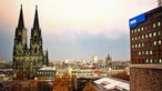 Der Kölner Dom unter dem Abendhimmel und das Archivhaus des WDR