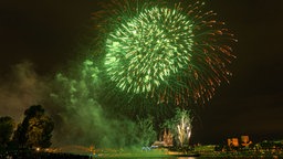 Ein grünes Feuerwerk leuchtet über den Rhein in Köln