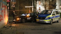 Polizisten stehen an einem beschädigten Auto