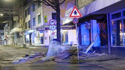 Auf dem Foto ist der komplett zerstörte Vorraum einer Bank. Auf einem Haufen Schutt vor der Bank liegt eine zersplissene Glastür.