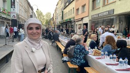 Eine Frau vor einer langen Tafel auf der Straße.