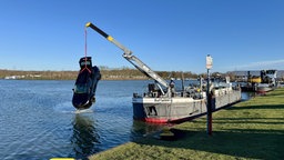 Schwarzer SUV hängt kopfüber am Kran über dem Rhein-Herne-Kanal 