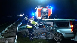 Einsatzkräfte untersuchen ein zerstörtes Auto