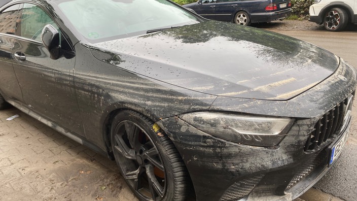 Schwarzer Mercedes mit Wasserrand und Schlamm auf der Motorhaube