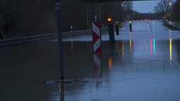 Es ist dunkel, die Straße ist komplett überschwemmt, im Wasser stehen beleuchete Verkehrsaufsteller