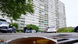 Das Foto zeigt das Hochhaus von außen von einem Parkplatz aus