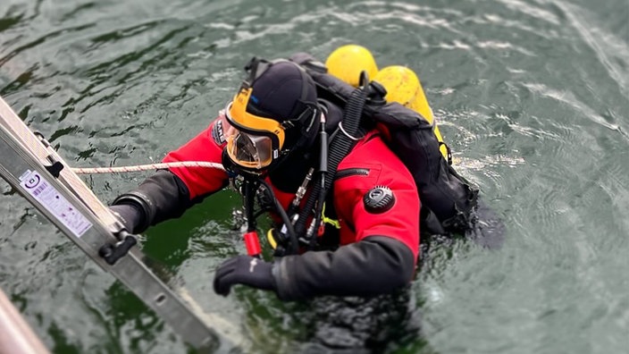 Ein Taucher klettert über eine Leiter ins Wasser.