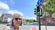 Eine Frau steht mit ihrem Fahrrad an der neuen Ampel.