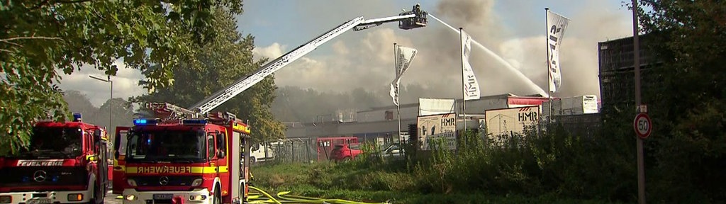 Zwei Feuerwehrwagen löschen eine verrauchte Halle