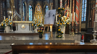 Der Altar in der Wallfahrtskirche in Kevelaer, ein Bild von Papst Franziskus, umstellt mit Blumen.