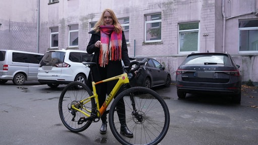 Das Bild zeigt die Reporterin mit dem Lokalzeit-Bike, einem Mountainbike mit gelbem Rahmen.