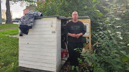 Ein Mann steht neben einem Tiny-House für Wohnungslose in Duisburg. 