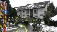 Mehrere Feuerwehrleute vor einem Mehrfamilienhaus