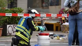 Feuerwehrmann hält einen Gegenstand über einem Behälter.