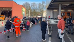 Mehrere Menschen stehen draußen in einer Schlange und warten auf ihren Obstbaum.