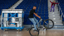 Die Street-Art-Show Urbanatix zieht von Bochum in die Essener Grudhalle. Auf dem Foto ist ein Fahrradfahrer zu sehen, der nur auf dem Hinterreifen fährt, auf der Tribüne tanzt eine Tänzerin.