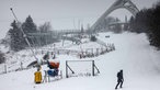 Ein Mann spaziert in Winterberg vor der Sprungschanze entlang.