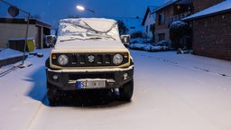 Ein geparkter Geländewagen ist mit Schnee bedeckt