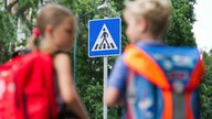 Zwei Grundschüler üben das richtige Überqueren einer Straße