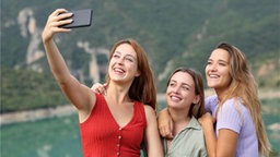 Eine Frau macht ein Selfie von sich und zwei weiteren Frauen.