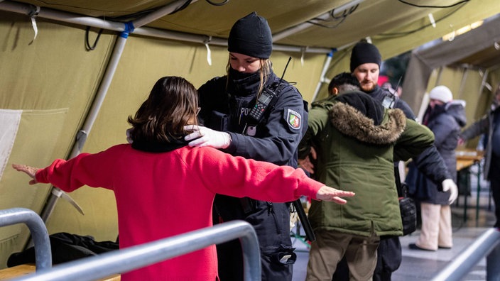 Polizisten stehen neben Zelten, wo Besucher und Teilnehmer der Messe kontrolliert werden