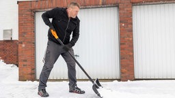 Ein Mann schippt Schnee vor seinem Haus