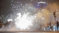 Böller und Raketen steigen auf der Straße in die Luft, während Passanten vorbeigehen