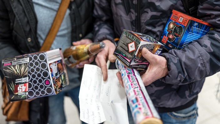 Kunden eines Supermarktes halten Feuerwerk in ihren Händen.