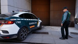 Ein spanischer Polizist Schaut auf ein Polizeiauto