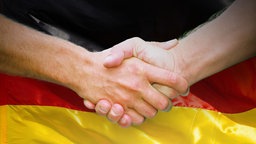 Zwei Hände schütteln sich vor einer Deutschland-Flagge