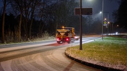 Ein Streufahrzeug streut auf einer mit Schneematsch bedeckten Straße