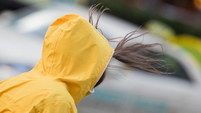 Sturmböe erfasst Passantin in Regenjacke