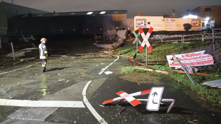 Ein Feuerwehrmann betrachtet die Trümmer und Schäden an einem Bahnübergang.