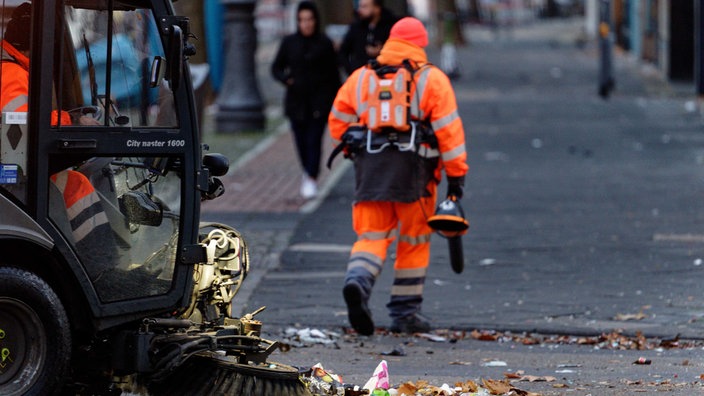 Ein Fahrzeug und ein Mitarbeiter der Abfallwirtschaftsbetriebe der Stadt Köln reinigt nach dem 11.11. eine Straße.