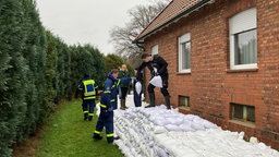 THW und freiwillige Helfer verdeichen das Wohnhaus mit Sandsäcken. 