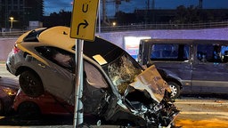 Ein stark beschädigtes Auto hängt nach einem Verkehrsunfall im Kölner Stadtteil Deutz über einem anderen Auto