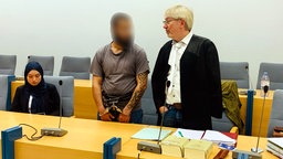 Die Dolmetscherin, der Täter sowie der Verteidiger (in der Reihenfolge von links nach rechts) im Gerichtssaal. 