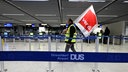 Ein Mann in Warnweste läuft mit einer ver.di Flagge über der Schulter durch den Check-In Bereich