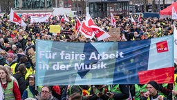 Ein Banner mit der Aufschrift «Für faire Arbeit in der Musik» und viele streikende Personen die dahinter stehen