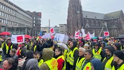 Viele Menschen in gelben Warnwesten und großen Transparenten versammelt auf einem großen Platz