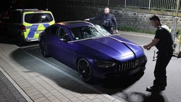 Ein beschädigter Mercedes AMG steht nach einem Unfall auf einer Straße in Remscheid Lennep. Polizeibeamte sichern Spuren an dem Fahrzeug. | Bildquelle: dpa / David Young Ein beschädigter Mercedes AMG steht nach einem Unfall auf einer Straße in Remscheid Lennep. Polizeibeamte sichern Spuren an dem Fahrzeug.