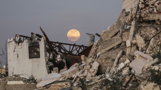 Der Vollmond geht am frühen Abend über zerstörten Gebäude im Zentrum des Gazastreifens auf.