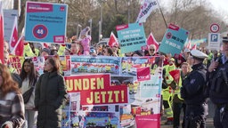 Streikende Menschen fordern mit bunten Schildern mehr Lohn in Bad Oeynhausen