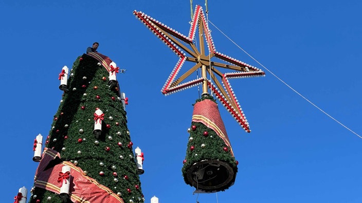 Die Spitze mit Stern wird auf den Weihnachtsbaum aufgesetzt