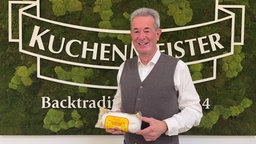 Kuchenmeister-Geschäftsführer Hans-Günter Trockels vor dem Logo