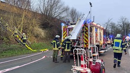 Feuerwehr Mitarbeiter*innen sind in ihrem Einsatz. Sie stehen auf der Straße und bereiten sich vor.