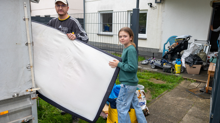 Eine Familie lädt einige Gegenstände auf einen Anhänger 