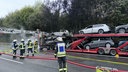 Fünf Feuerwehrmänner löschen einen brennenden Transporter. Dieser hat PKWs beladen.